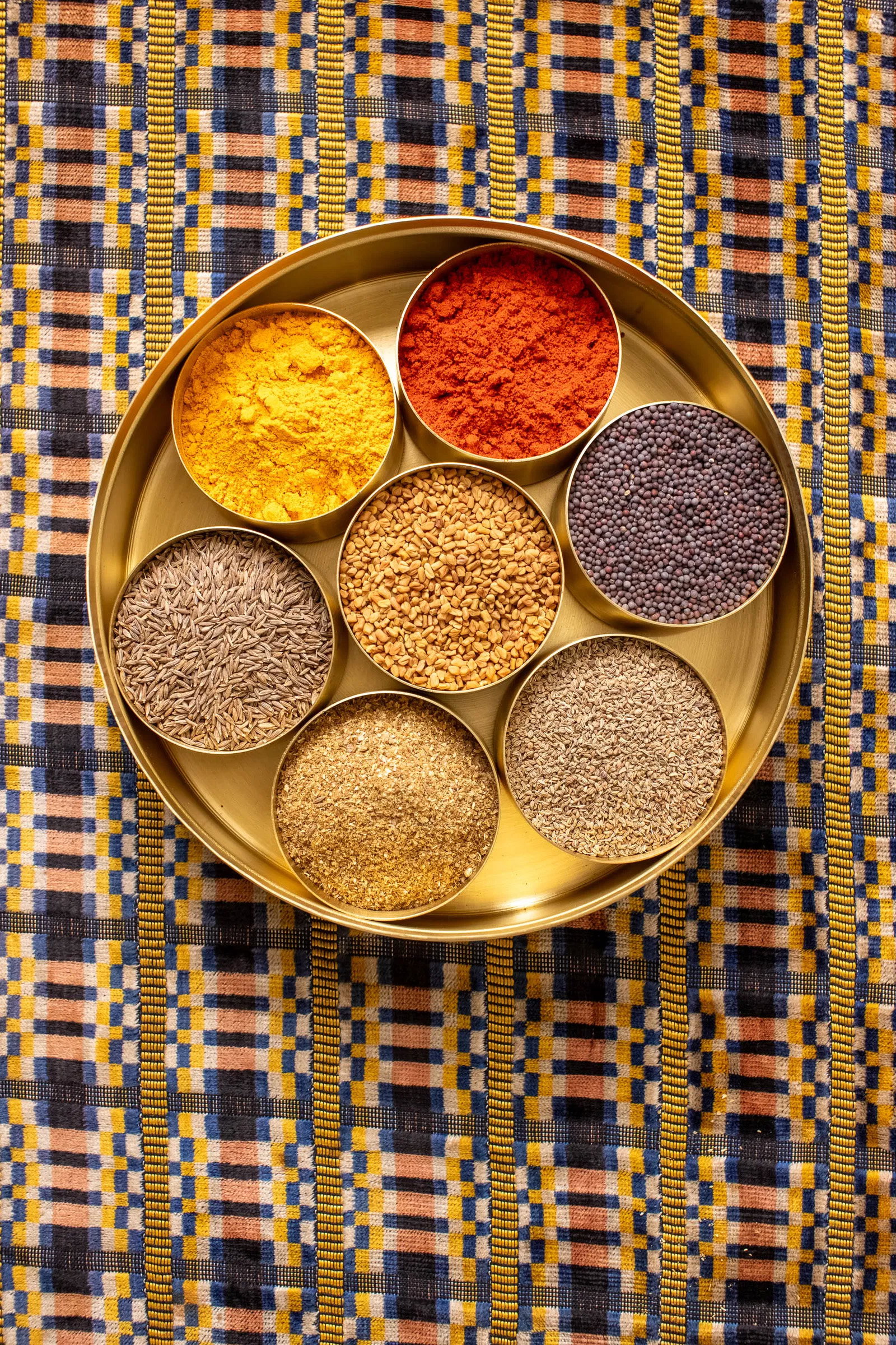 Top shot of brass masala dabba, without lid, filled with spices.