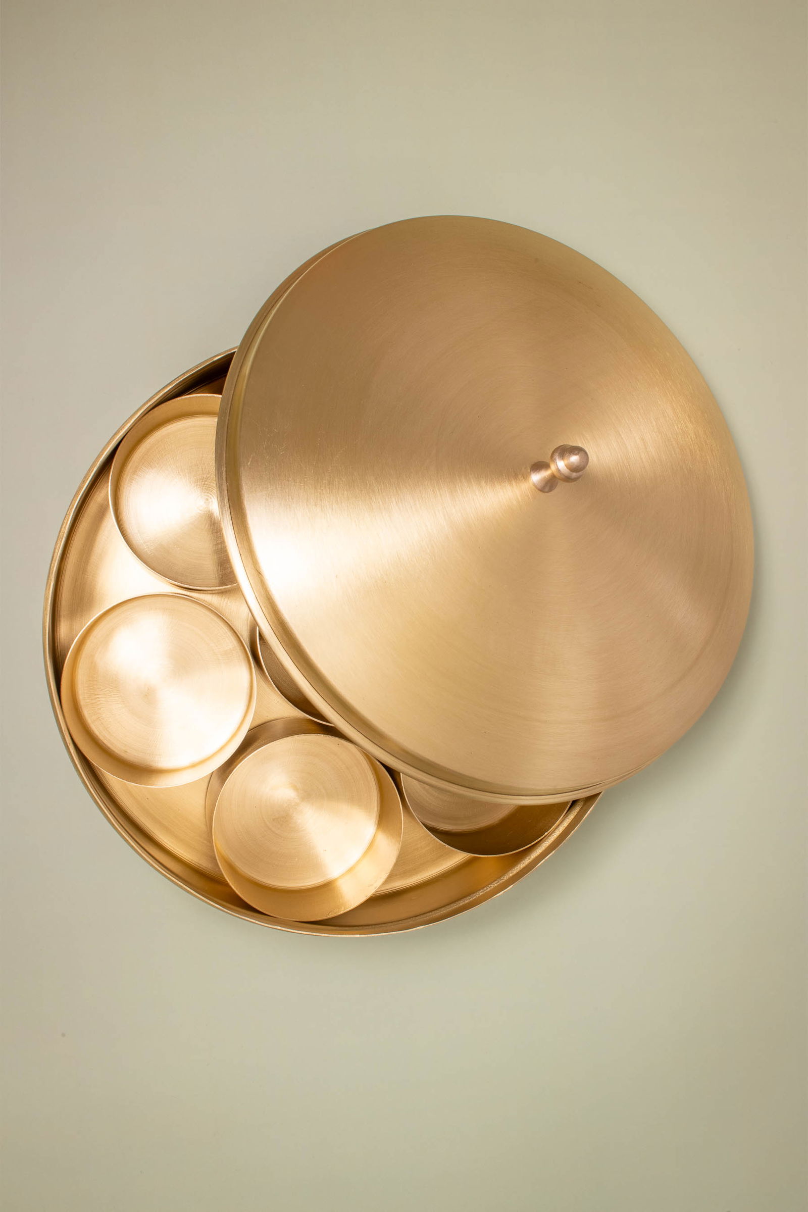 Brass masala dabba with lid slightly ajar, no spices.