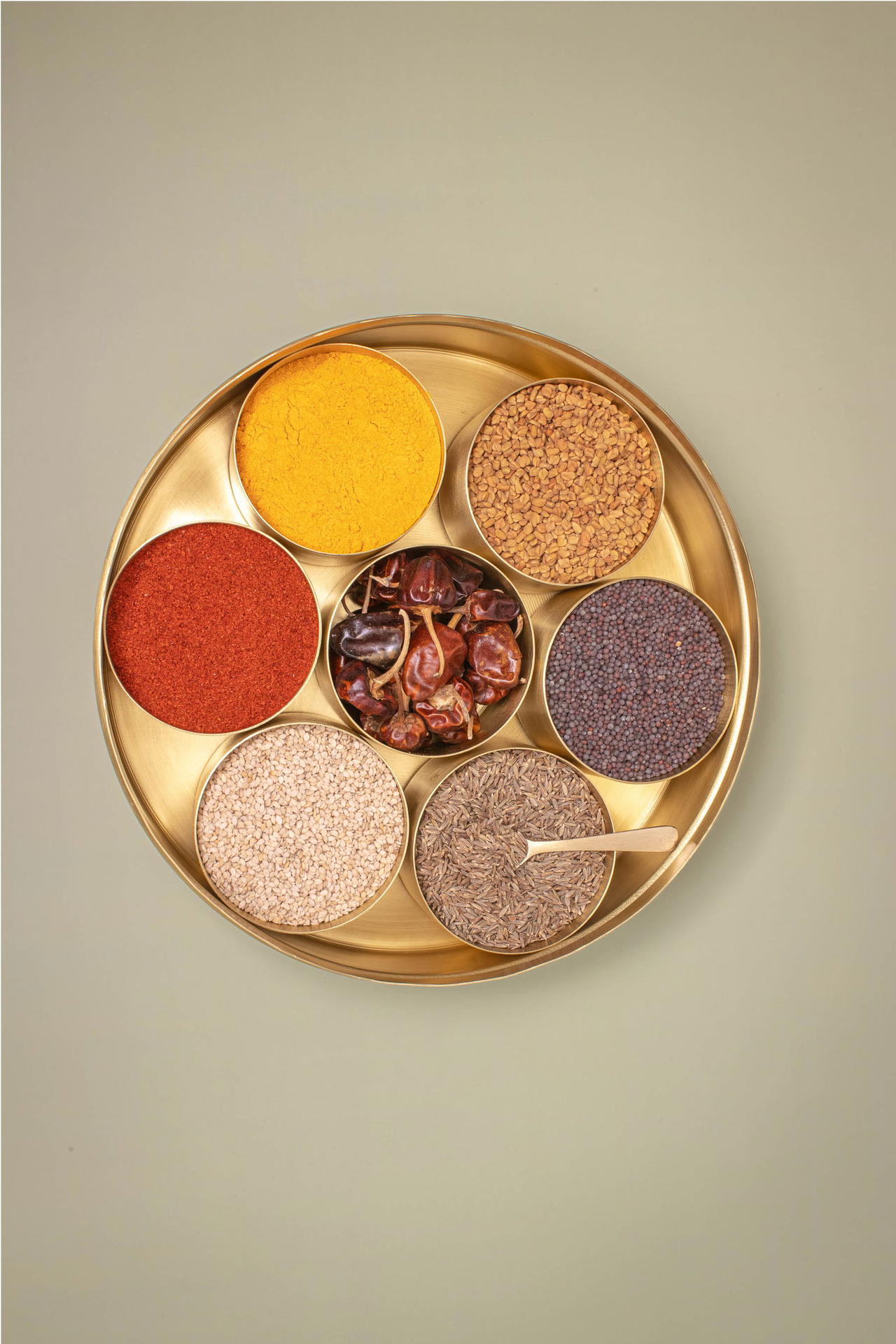 Brass dabba shown from the top, filled with spices